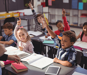 happy children with their hands raised who are excited to be in class