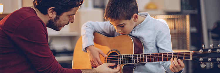 music teacher helps young student play guitar