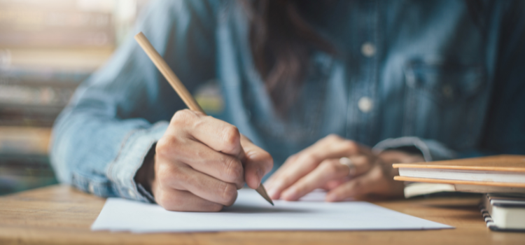woman writing on paper using a pencil