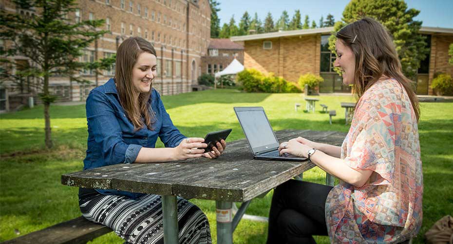 two college students talking while taking a break outside on a college campus