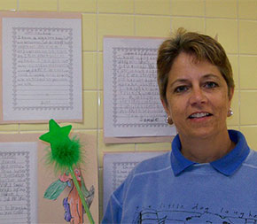 special education teacher in classroom next to student papers hanging on wall