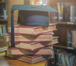 bachelors in education graduation cap resting on books