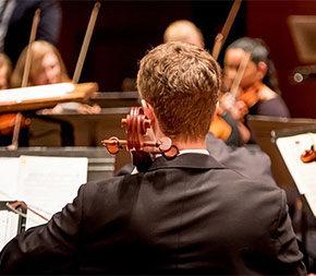 music teacher conducting school student symphony performance