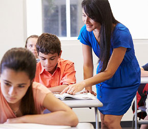 female teacher with master's in teaching works with her classroom on textbook curriculum