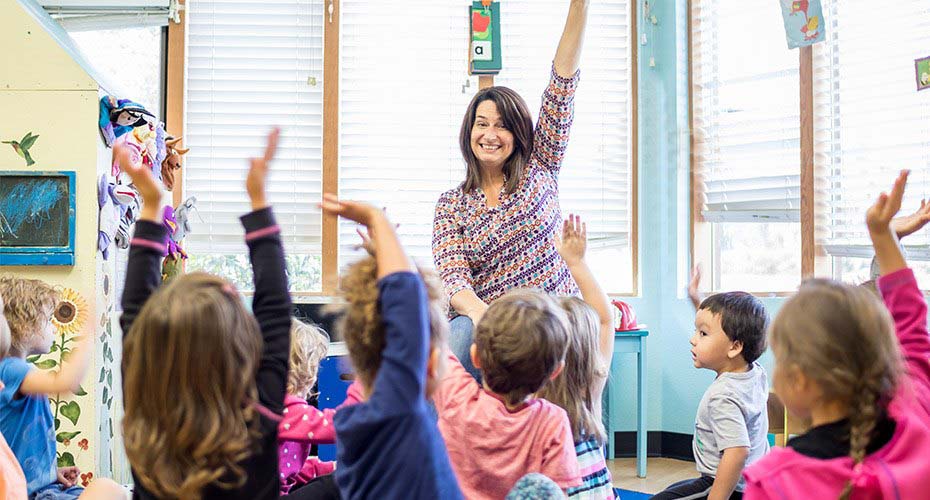 enthusiastic teacher with special education degree encourages class of special needs kids to raise hands