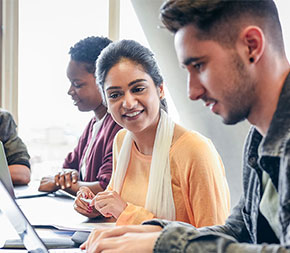 four foreign students study on laptops together