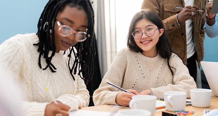 two college students filling out forms at coffeehouse