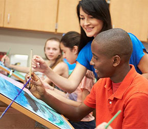 high school art teacher helps students in painting class