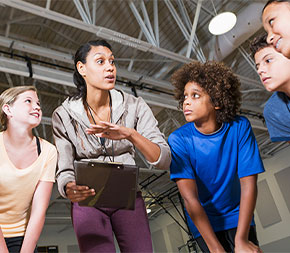 woman teacher with group of young students in gym