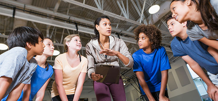 woman teacher with group of young students in gym