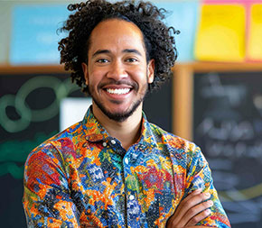 substitute teacher stands in front of backboard in classroom