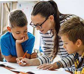 substitute teacher works with children and corrects their notebooks as a group