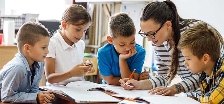substitute teacher works with children and corrects their notebooks as a group